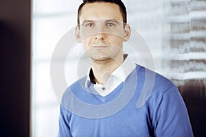 Friendly adult businessman in blue sweater. Business headshot or portrait in sunny office