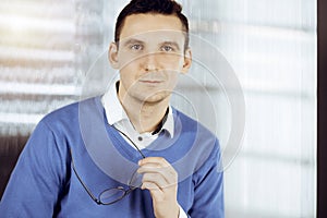 Friendly adult businessman in blue sweater. Business headshot or portrait in sunny office