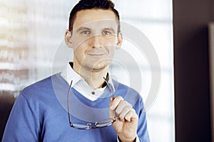 Friendly adult businessman in blue sweater. Business headshot or portrait in sunny office