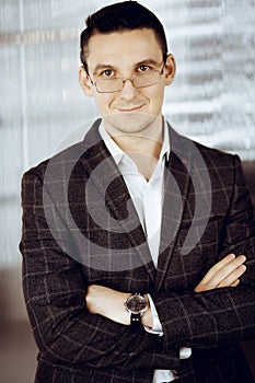 Friendly adult businessman in grey jacket. Business headshot or portrait in sunny office