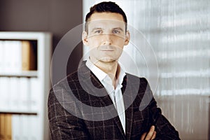 Friendly adult businessman in grey jacket. Business headshot or portrait in sunny office