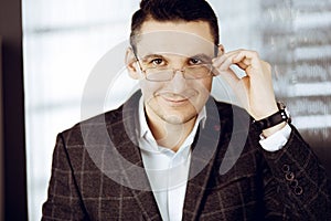 Friendly adult businessman in grey jacket. Business headshot or portrait in sunny office