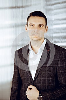 Friendly adult businessman in grey jacket. Business headshot or portrait in sunny office