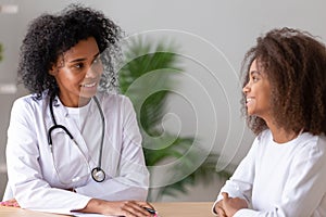 Friendly african american female doctor talking to teen girl patient