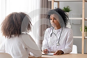 Friendly African American pediatrician doctor talking to teen girl