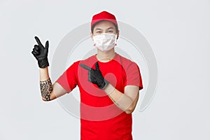 Friendly asian courier in red uniform and cap, wear protective medical mask and gloves for safe delivery of parcels to