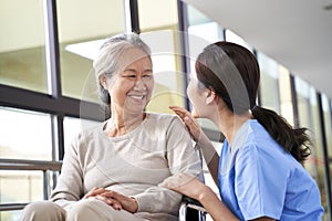 Friendly asian staff talking to senior resident in nursing home