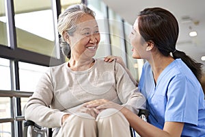 Friendly asian staff talking to senior resident in nursing home