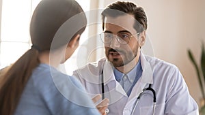 Friendly attentive confident male doctor consulting young woman patient