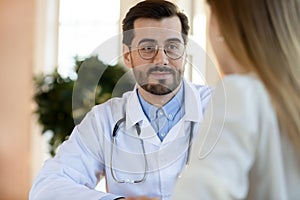 Friendly attentive male doctor listening to complaints of female patient