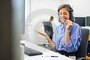 Friendly beautiful customer service agent woman chatting with client using hands-free headset at office