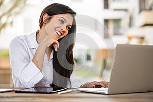 Friendly beautiful mixed ethnicity student using laptop computer to video chat, studying, communicating online on university campu