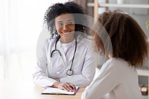 Friendly black therapist listening adolescent girl during reception