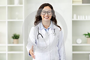 Friendly brunette european woman doctor outstretching hand