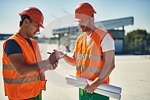 Friendly builder talking and his colleague making notes