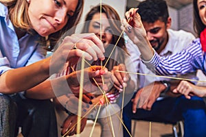 Friendly business team having fun at corporate training, funny teambuilding activity, playing spaghetti game