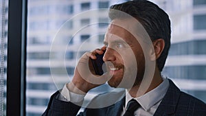 Friendly businessman talking phone making corporate call in modern window office