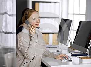 Friendly businesswoman talking by headset in office. Call center and diverse people group in business