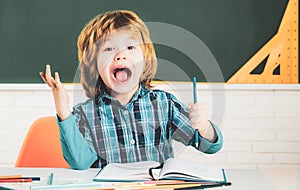 Friendly child in classroom near blackboard desk. Kids gets ready for school. Happy cute industrious child is sitting at