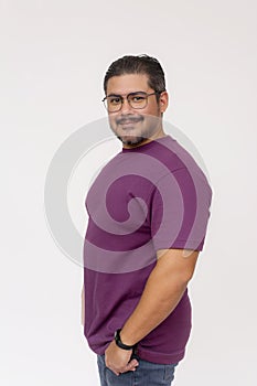 A friendly chubby man of mixed ancestry wearing glasses. Half body photo, quarter turn pose, wearing purple waffle shirt and jeans
