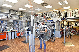 Friendly and competent bicycle mechanic in a workshop repairs a bike