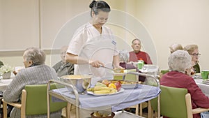 Friendly cook serving food to seniors in a nursing home