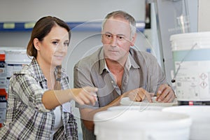 friendly couple choosing paint bucket in housewares hypermarket