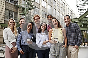 Friendly coworkers laugh to camera outside their workplace photo
