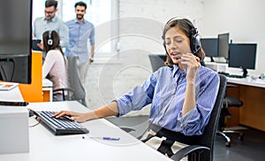 Friendly customer service adviser talking to a customer at call center office.
