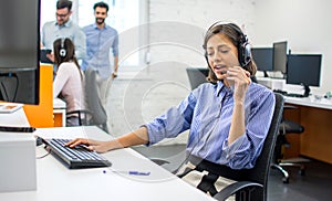 Friendly customer service adviser talking to a customer at call center office