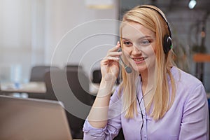 Friendly customer support operator with headset working at call center