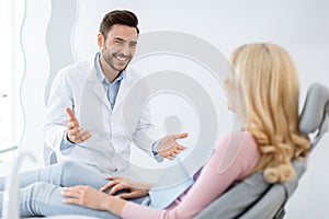 Friendly dentist having conversation with blonde woman patient