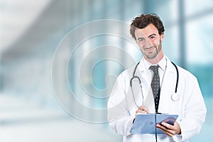 Friendly doctor with clipboard smiling standing in hospital hallway