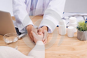 Friendly doctor hands holding patient hand sitting at the desk f