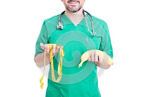 Friendly doctor holding banana and tape line