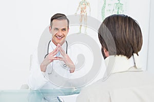 Friendly doctor listening to patient with concentration at desk