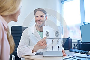 Friendly doctor offering different deaf aids to his a patient