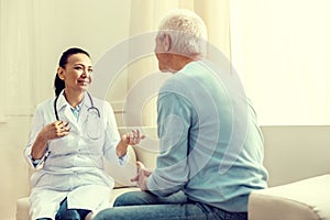 Friendly doctor smiling while consulting retired gentleman