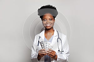 Friendly doctor woman holding pill tablet on white background