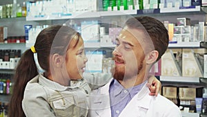 A friendly druggist is holding a little girl in her arms