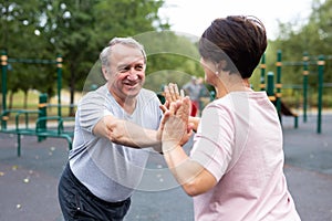 Friendly family couple doing gymnastic exercises together in summer city park