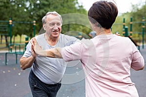 Friendly family couple doing gymnastic exercises together in summer city park