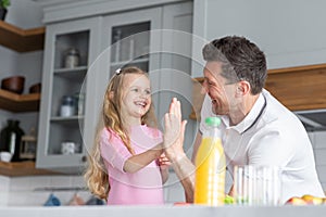 A friendly family from father with daughter stand and manage in the kitchen. A young serious man dad gives his child