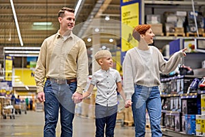 friendly family with little boy son walking through household appliances section in supermarket aisle