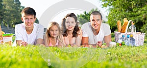 Friendly family lying on green lawn at picnic