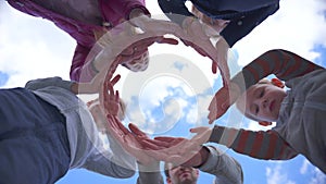 A friendly family makes a circle out of their hands against the blue sky
