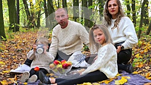 Friendly family on a picnic in the autumn forest.