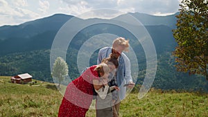 Friendly family using smartphone in mountains. Couple with kids looking to phone