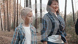 Friendly family walking on pine forest at vacation. Mom, son, father and daughter walking in woodland. Family hiking in