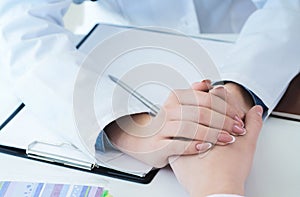 Friendly female doctor hands holding patient hand sitting at the desk for encouragement, empathy, cheering and support